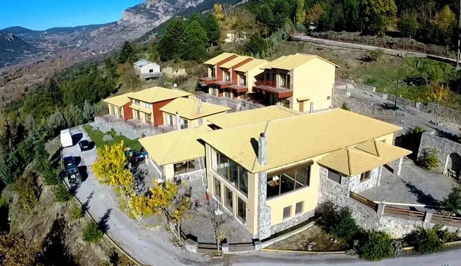 Το ξενοδοχείο από ψηλά, ανάμεσα στα έλατα, με τον κάμπο πίσω
